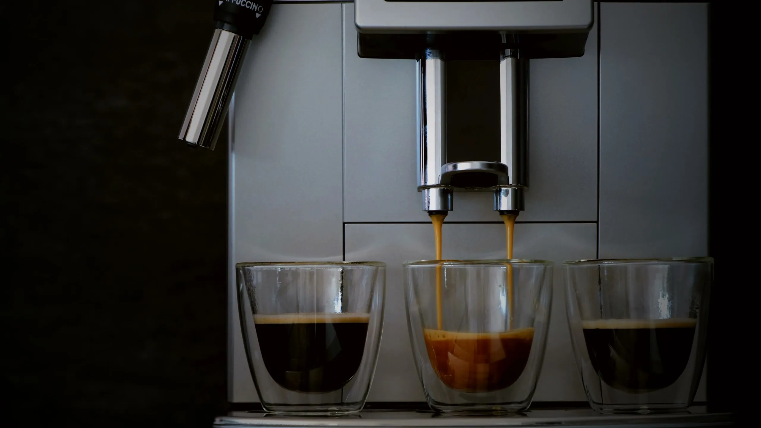 Stainless-steel espresso machine pouring espresso into three glasses
